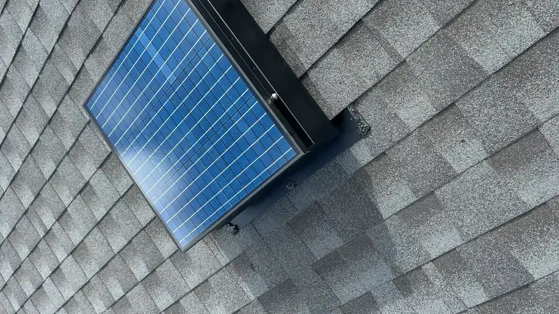Solar attic fan seated flush against surrounding shingles