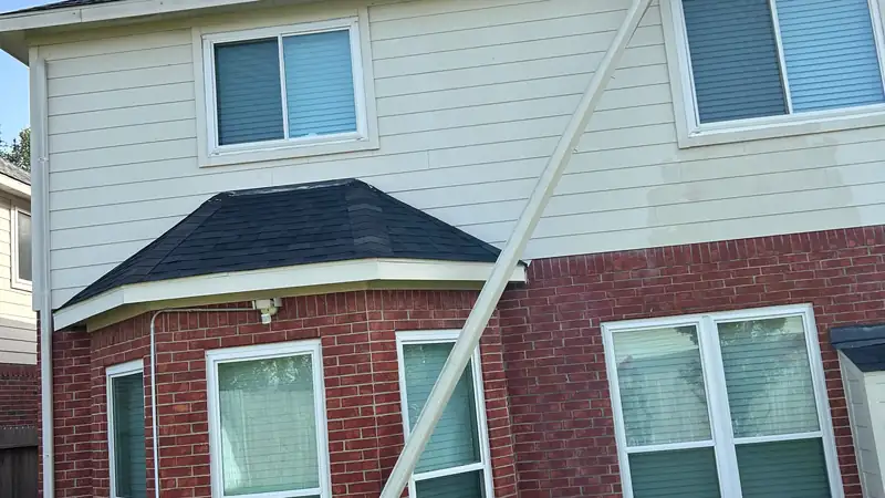 Downspout pulled loose and hanging diagonally across the side of a brick home