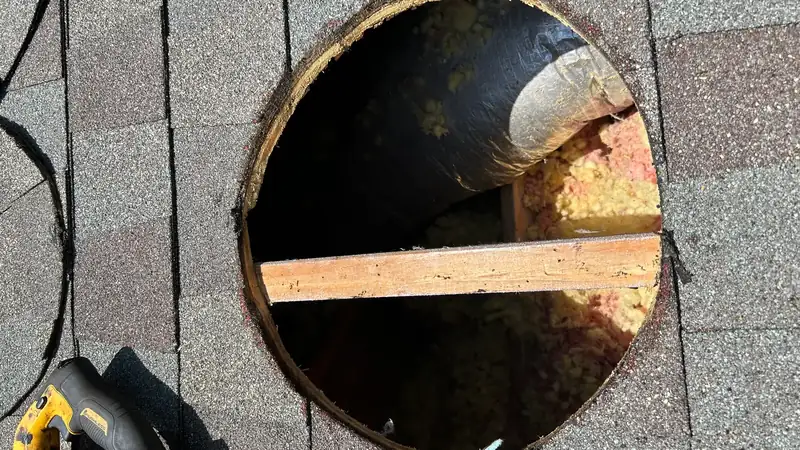 Roof opening with a reciprocating saw beside it during a solar attic fan install